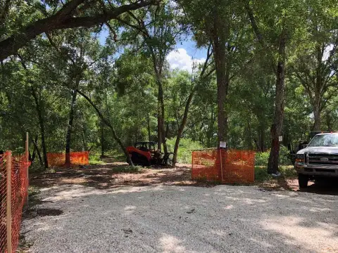 Skid steer and truck behind tree-protection fencing on commercial tree service job in DeLand, FL